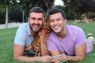 Gay couple in the park with their pet bengal cat